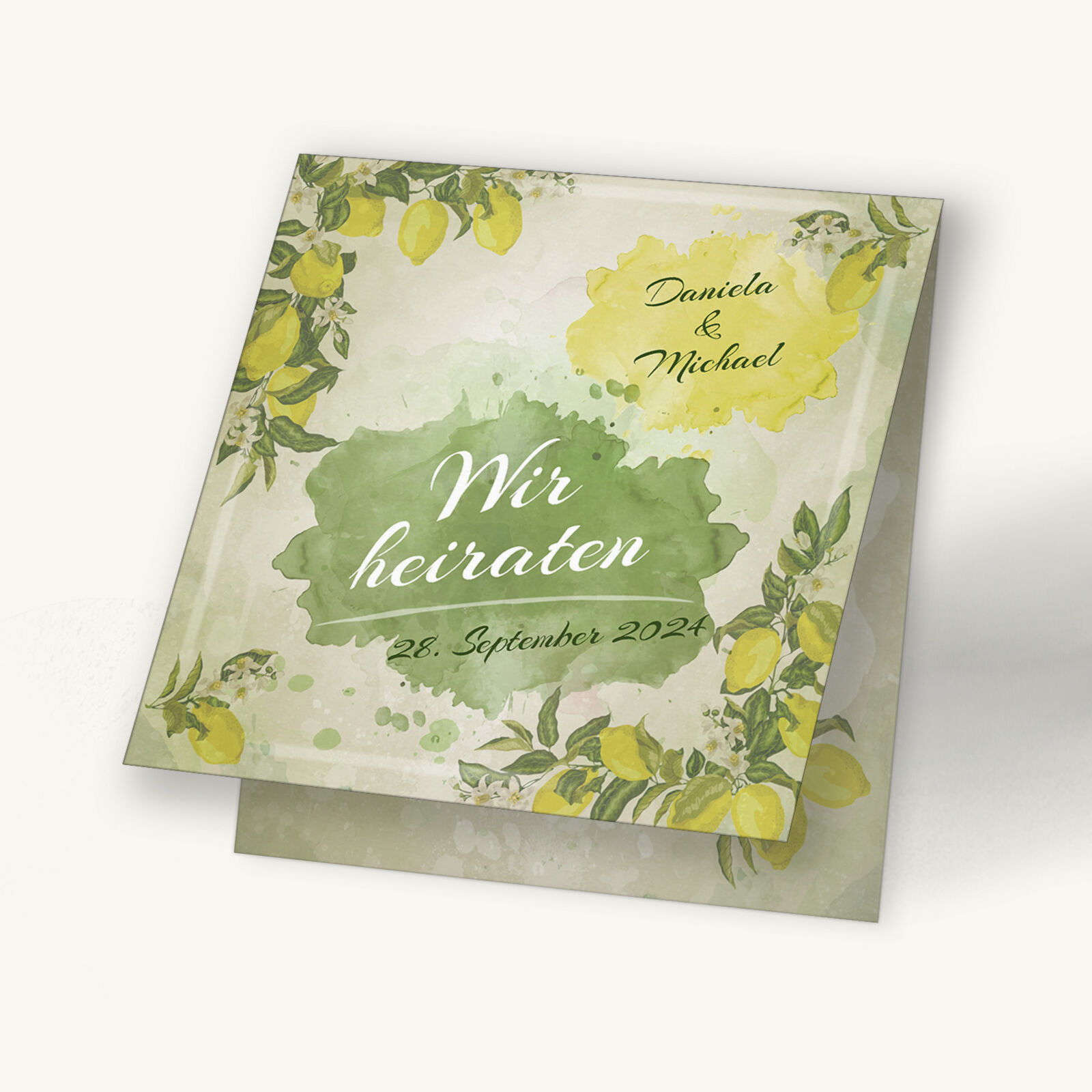 Hochzeitseinladungskarte im frischen Zitronen-Design. Sanftes Grün und leuchtendes Gelb schaffen eine fröhliche, mediterrane Stimmung. Umrahmt von zarten Blättern und Zitronenzweigen stehen die Namen „Daniela & Michael“ sowie der Schriftzug „Wir heiraten“. Das Design wirkt natürlich, elegant und sommerlich leicht.