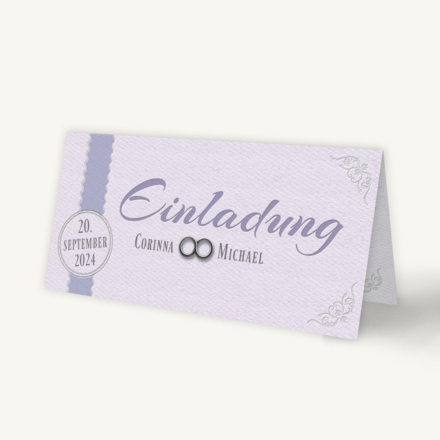 Einladungskarte zur Silberhochzeit im romantischen Design mit zartem Fliederton. In der Mitte steht in eleganter Schrift 'Einladung', darunter die Namen Corinna und Michael mit zwei silbernen Ringen. Links befindet sich ein Kreis mit dem Datum '20. September 2024'. Feine Ornamentverzierungen schmücken die Ecken.