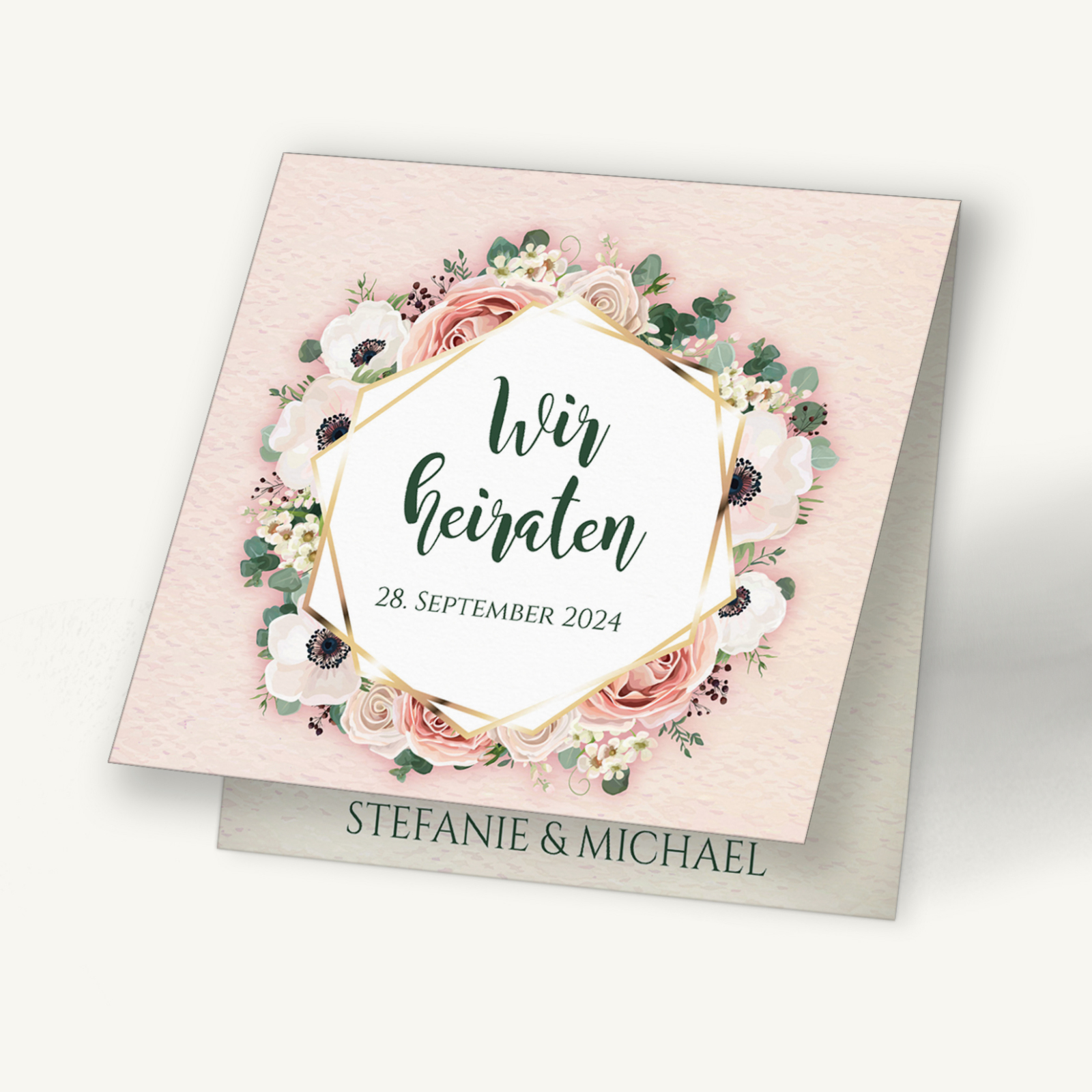 Hochzeitseinladungskarte mit romantischem Blumenkranz aus Rosen und Anemonen in Rosa- und Cremetönen. In der Mitte steht in moderner Handschrift „Wir heiraten“. Darunter die Namen „Stefanie & Michael“. Das Design wirkt zart, festlich und liebevoll – ideal für eine stilvolle Hochzeit.