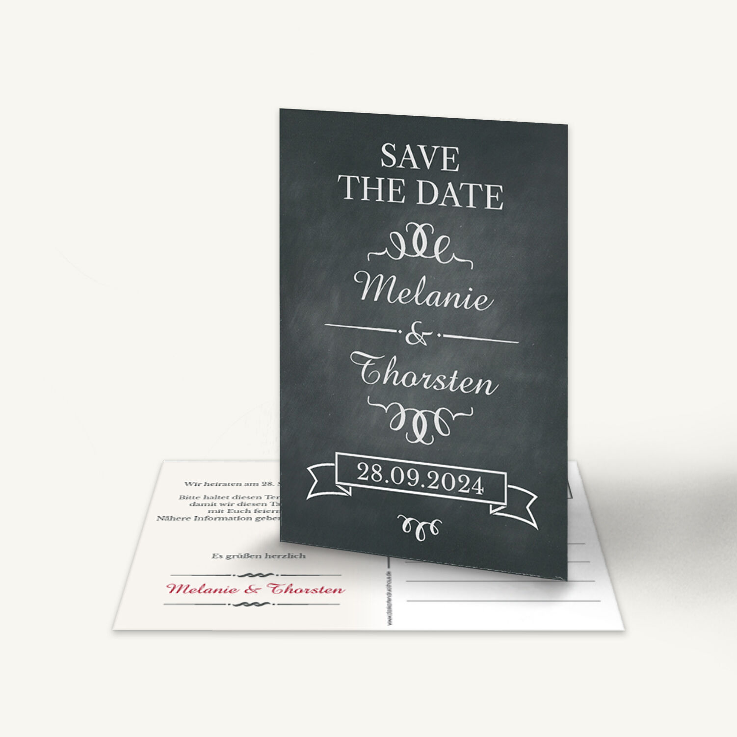 Elegante Save-the-Date Karte im Tafellook mit dunklem Kreidetafel-Hintergrund. Weißer Schriftzug: 'Save the Date Melanie & Thorsten 28.09.2024'. Verspielte Ornamente und Schleifenrahmen. Rückseite mit den Namen in Rot. Stilvoll und modern.