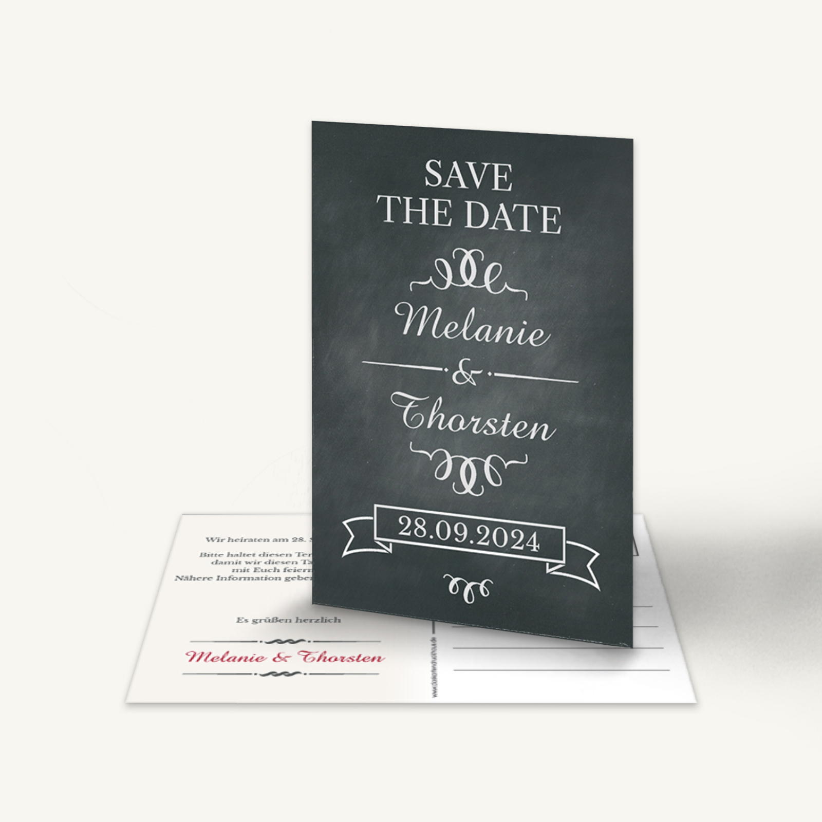 Elegante Save-the-Date Karte im Tafellook mit dunklem Kreidetafel-Hintergrund. Weißer Schriftzug: 'Save the Date Melanie & Thorsten 28.09.2024'. Verspielte Ornamente und Schleifenrahmen. Rückseite mit den Namen in Rot. Stilvoll und modern.